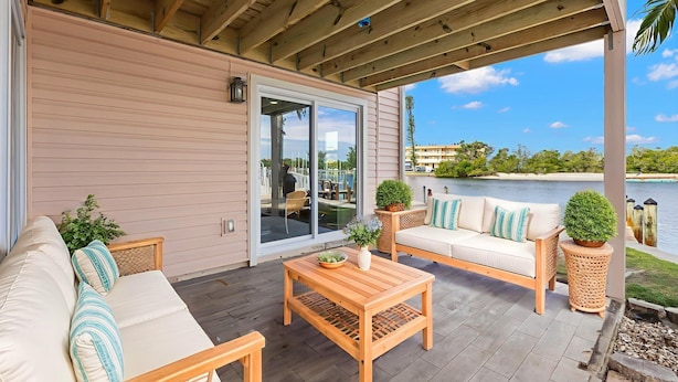A covered patio with a sofa, a table, and potted plants. - Turtle Nest (Sarasota)