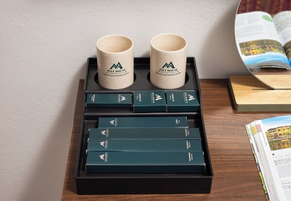 Un plateau avec deux tasses beiges et plusieurs livres vert foncé, posés sur une table en bois.