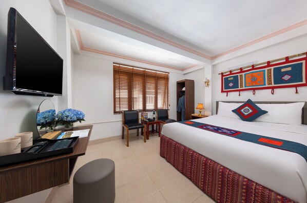 A hotel room with a bed, a desk with a computer, a TV, and a window with blinds. - July House Central Sapa (Sa Pa)