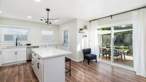 Una cocina moderna con armarios blancos, una isla de mármol y una silla negra.