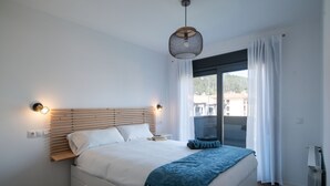 A bedroom with a bed, bedside lamps, a window with curtains, and a radiator. - Ribadesella House with Garden 2 km from Beach – Saelia (Ribadesella)