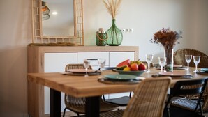 A dining area with a wooden table set for four, surrounded by wicker chairs. - Ribadesella House with Garden 2 km from Beach – Saelia (Ribadesella)