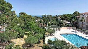 A pool area with a view of the sea, surrounded by trees and buildings. - Le Grand Parc by Interhome (Saint Aygulf)