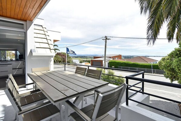 An outdoor patio with a table and chairs, overlooking a residential area with houses and a flag.