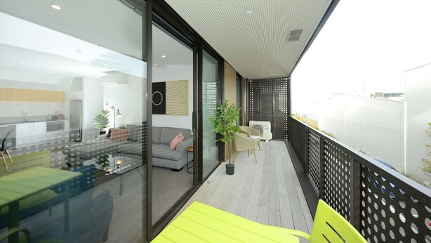 A modern apartment with a balcony, a dining area, and a living room with a sofa and a coffee table. - Relax and Unwind Central City Hideaway with Carpark (Christchurch)