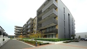 A modern multi-story residential building with balconies, a landscaped courtyard, and a parking area. - Relax and Unwind Central City Hideaway with Carpark (Christchurch)