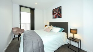 A hotel room with a bed, a chair, a nightstand, and a painting on the wall. - Relax and Unwind Central City Hideaway with Carpark (Christchurch)