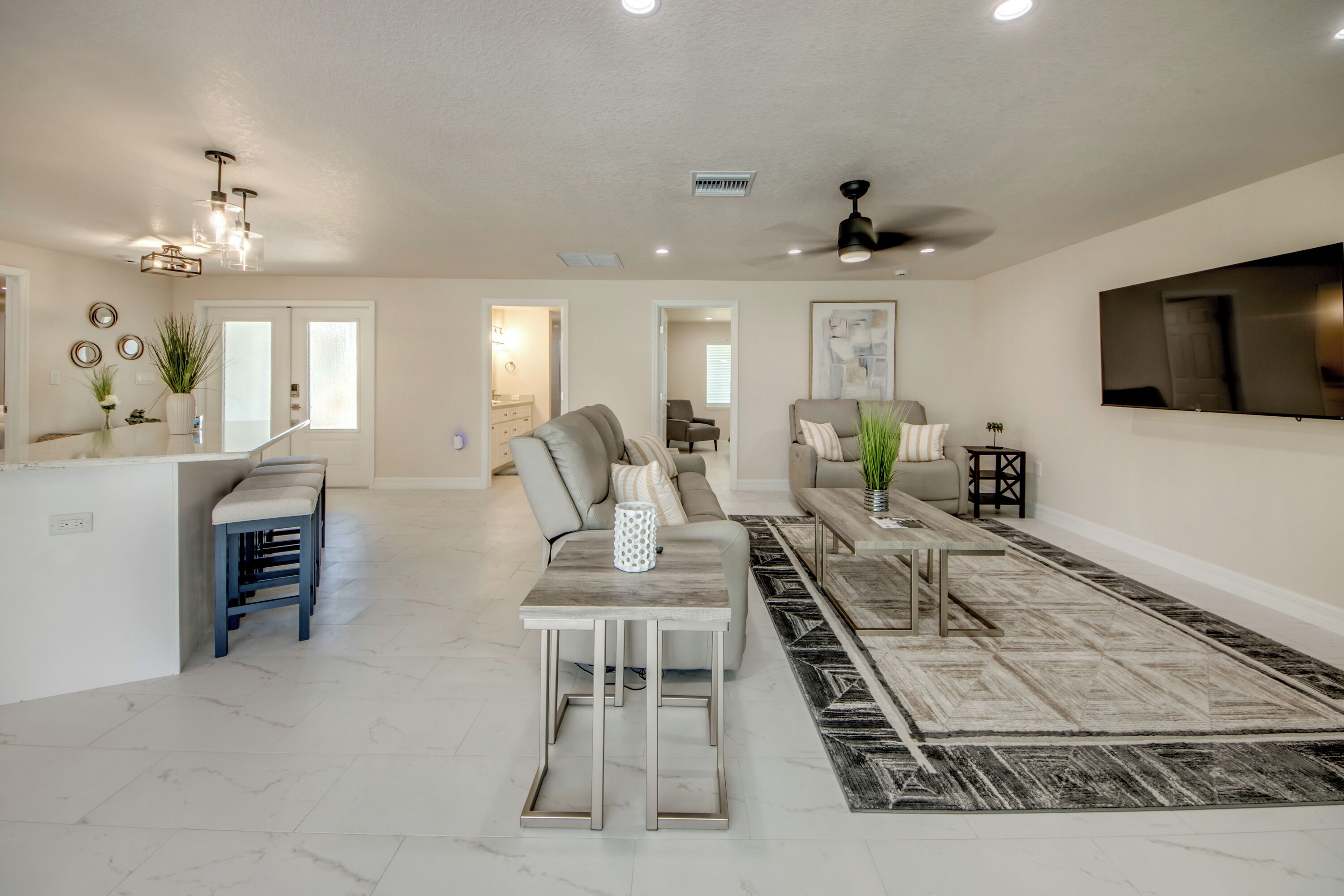 A spacious living area with a kitchen island, seating, and a large TV.