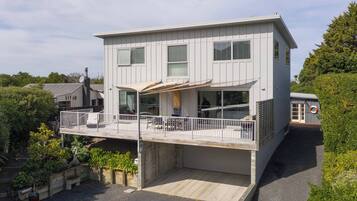 A modern two-story house with a balcony, a covered patio, and a garage.