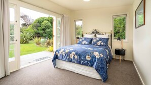 Une chambre avec un grand lit, une table de chevet et une fenêtre donnant sur un jardin.