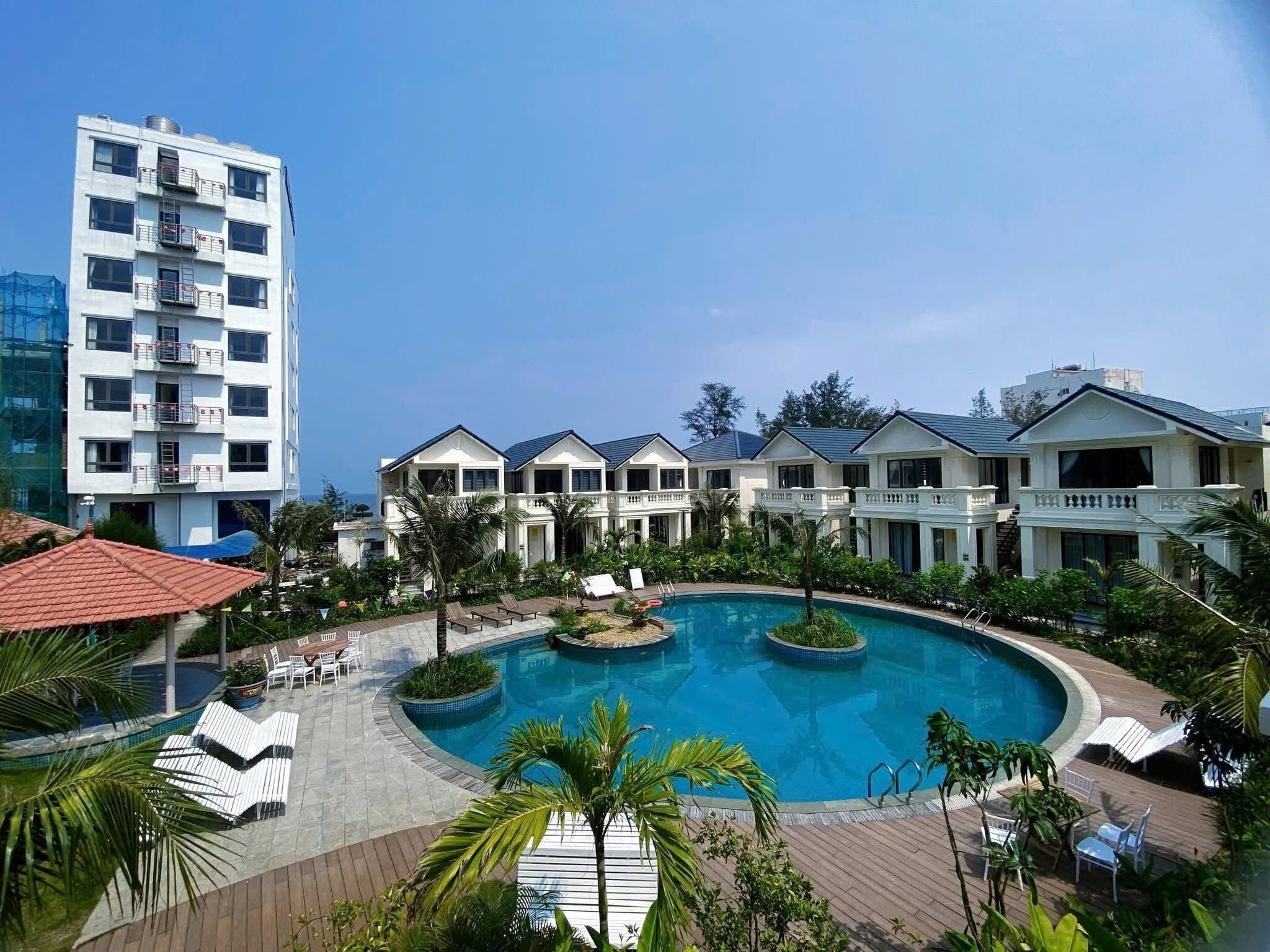 A hotel with a swimming pool, multiple guest rooms, and a tall building in the background.