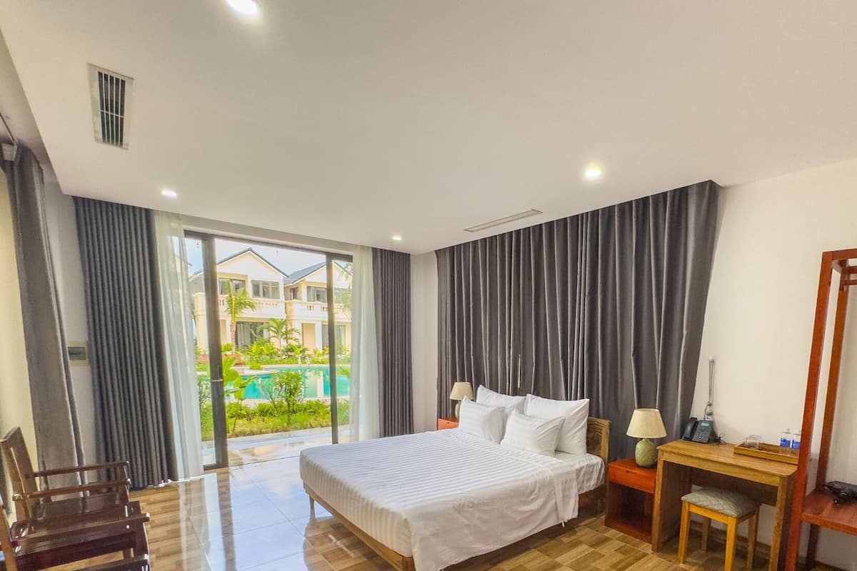 A hotel room with a bed, a desk, a chair, and a view of a swimming pool.