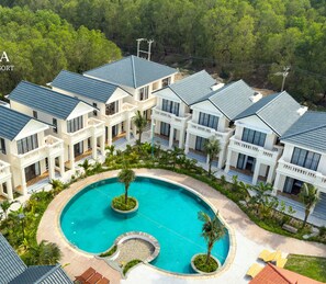 A resort with multiple white buildings, a central swimming pool, and lush greenery. - Nava Hotel & Resort (Dong Hoi)