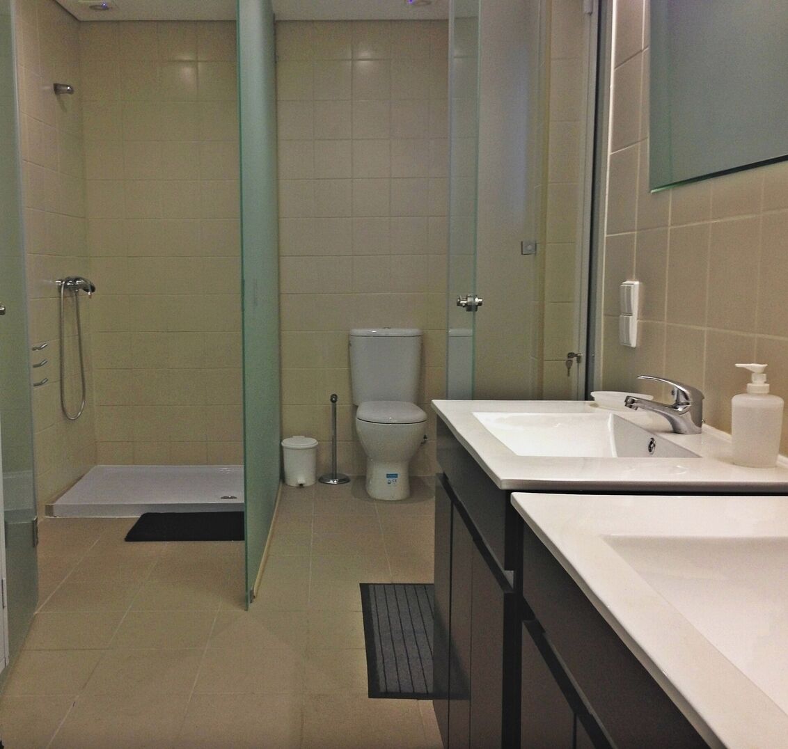 A modern bathroom with a shower, toilet, and sink.
