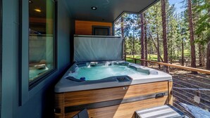 Un jacuzzi sur un balcon avec vue sur une forêt.