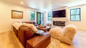 Un salon moderne avec une cheminée, des meubles en cuir et de grandes fenêtres.