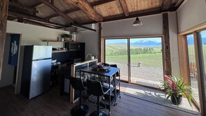Cocina rústica con vigas de madera, refrigerador, estufa y un ventanal con vistas a montañas.