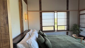 Un dormitorio de estilo japonés tradicional con suelo de tatami, una cama de madera baja y una puerta corrediza tipo shoji.
