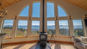 Un'ampia stanza con soffitto alto e grandi finestre ad arco che si affacciano su una vista montuosa.