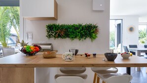 Una cocina moderna con encimera de madera, un frutero, una cafetera y una planta en la pared.