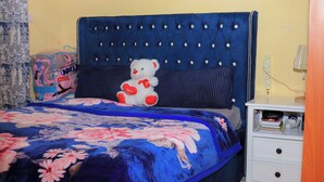 Ein Schlafzimmer mit einem Bett, einem Nachttisch und einem Teddybären.