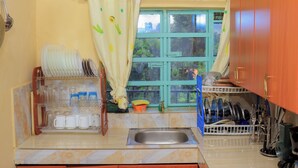 Eine Küche mit Spüle, Geschirrgestell und einem Fenster mit Vorhängen.
