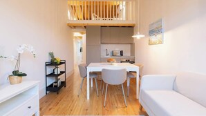 Un espace de vie compact comprenant un coin repas, une kitchenette et une chambre en mezzanine.