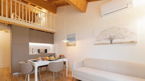 Une cuisine moderne avec un coin repas, un canapé blanc et un tableau représentant un arbre.