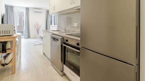 A modern kitchen with stainless steel appliances, a wooden table with a coffee machine, and a view of the living area. - Modern & Bright Studio by HostWise (Porto)