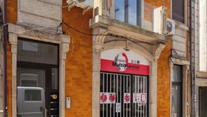 A building with a red and white sign reading "Espace MultiMarcial" and a barred entrance. - Modern & Bright Studio by HostWise (Porto)