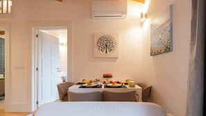 Een hotelkamer met een bed, een ontbijttafel en een schilderij, plus een airconditioning.