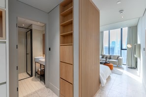 Una habitación de hotel moderna con un ventanal grande, un sofá, una cama y un separador de madera.