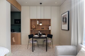 A compact living space with a kitchenette, a dining area with a table and chairs, and a sofa.