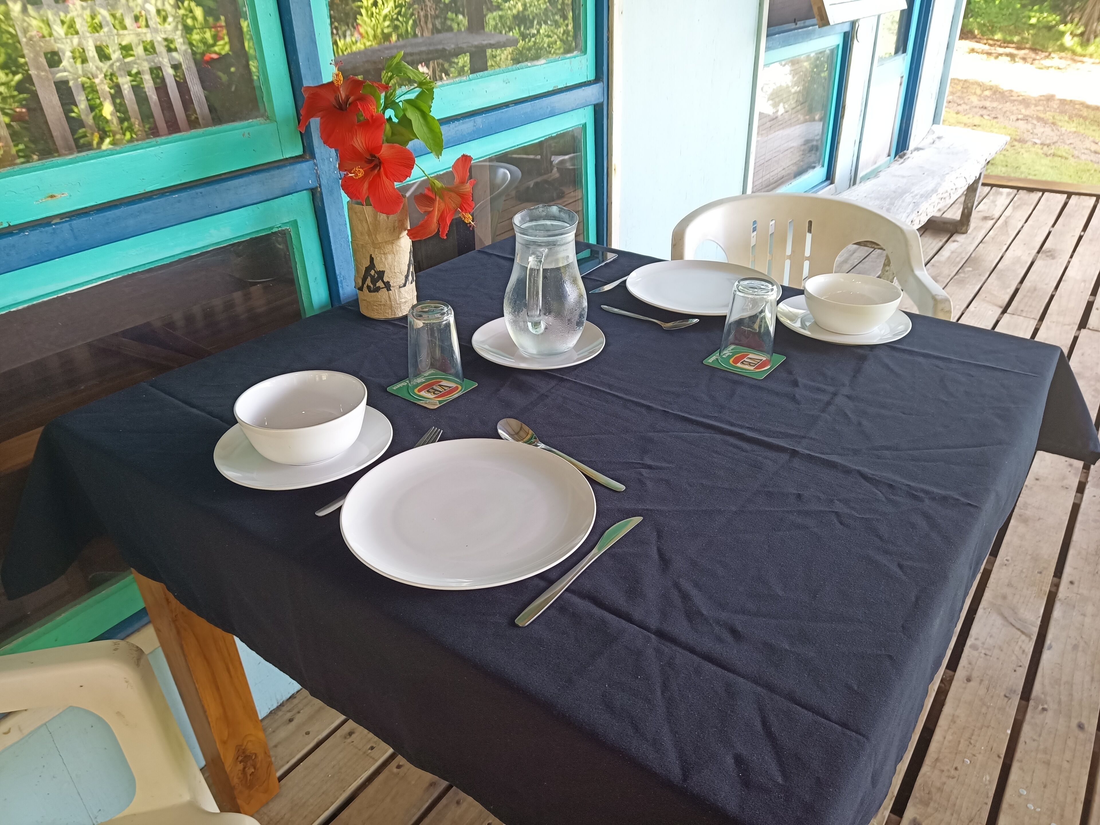 A table set for two with white plates, bowls, cutlery, and a glass pitcher.