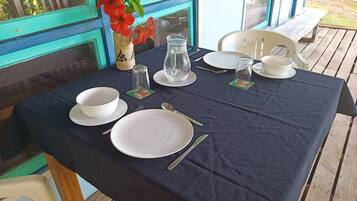 A table set for two with white plates, bowls, cutlery, and a glass pitcher.