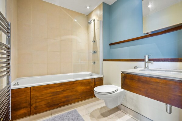 A modern bathroom with a bathtub, toilet, and sink.