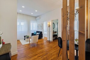 Uma sala de estar moderna com sofá, mesa de jantar e cozinha visível por uma porta aberta.