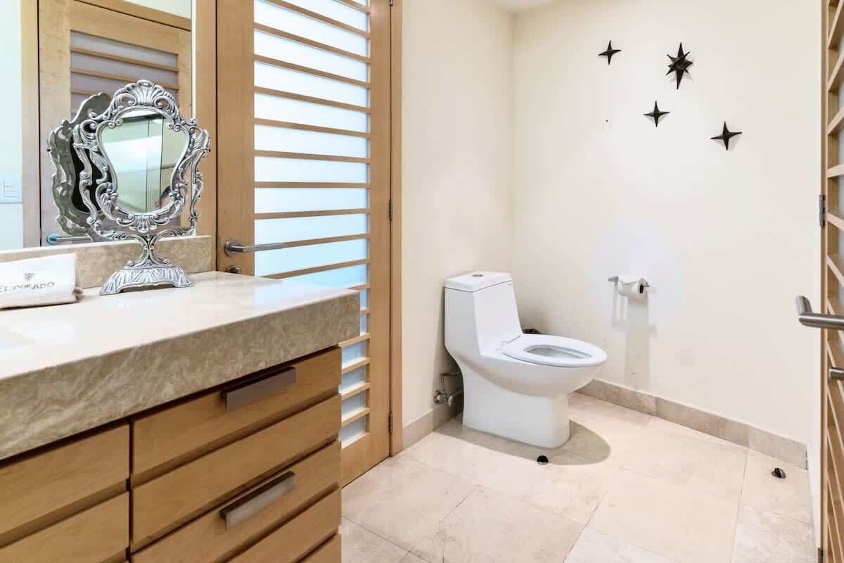 Une salle de bain avec un comptoir en marbre, des meubles en bois, des toilettes blanches et des décorations murales en forme d’étoiles.