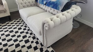 En stribet sofa med et blåt tie-dye tæppe, et sort-hvidt skakternet tæppe og to sorte stole.