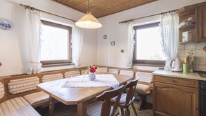 A cozy kitchen with wooden cabinets, a dining table with benches, and a hanging light fixture. - Landhaus Rittisweid by Interhome (Schladming)