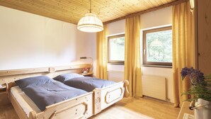 A wooden bedroom with two beds, a window, and a hanging light fixture. - Landhaus Rittisweid by Interhome (Schladming)