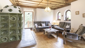 Ein gemütliches Wohnzimmer mit Holzboden, einem grünen Dekorationsstück, einer Sofagarnitur und einem Couchtisch aus Holz.