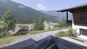 Eine Berglodge mit Holzfassade, einer Schotterauffahrt und Blick auf ein bewaldetes Tal.
