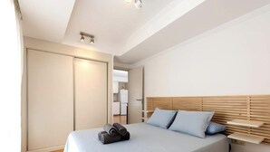 A modern bedroom with a large bed, wooden headboard, and a built-in nightstand.