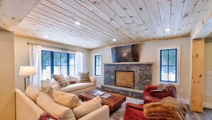 Una sala de estar acogedora con chimenea, un sofá, un sillón rojo y una mesa de centro.