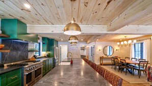 Una cocina amplia con una isla central, armarios verdes y una estufa de acero inoxidable.