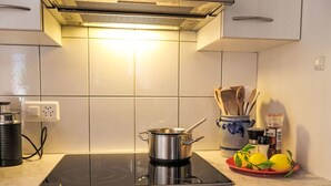 A kitchen with a stove, a pot on the counter, a spice jar, and a bowl of lemons. - Haus Europa by Interhome (Kandersteg)