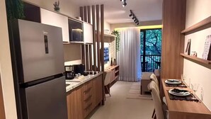 A modern kitchen with a built-in refrigerator, wooden cabinets, and a dining area with a table set for two. - Luxurious studio in the city of Rio (Centro Rio de Janeiro)