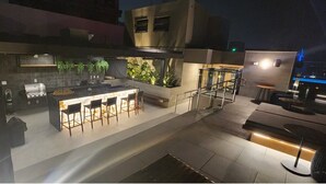 An outdoor kitchen area with bar stools, a grill, and potted plants. - Luxurious studio in the city of Rio (Centro Rio de Janeiro)