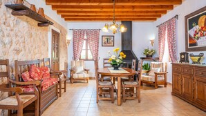 Un salon chaleureux avec des meubles en bois, une cheminée et un coin repas comprenant une table et des chaises.